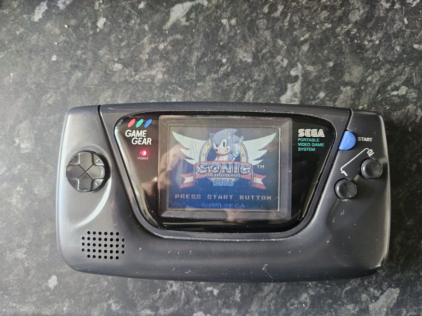 The repaired Sega Game Gear back in its case, showing a clean Sonic the Hedgehog title screen