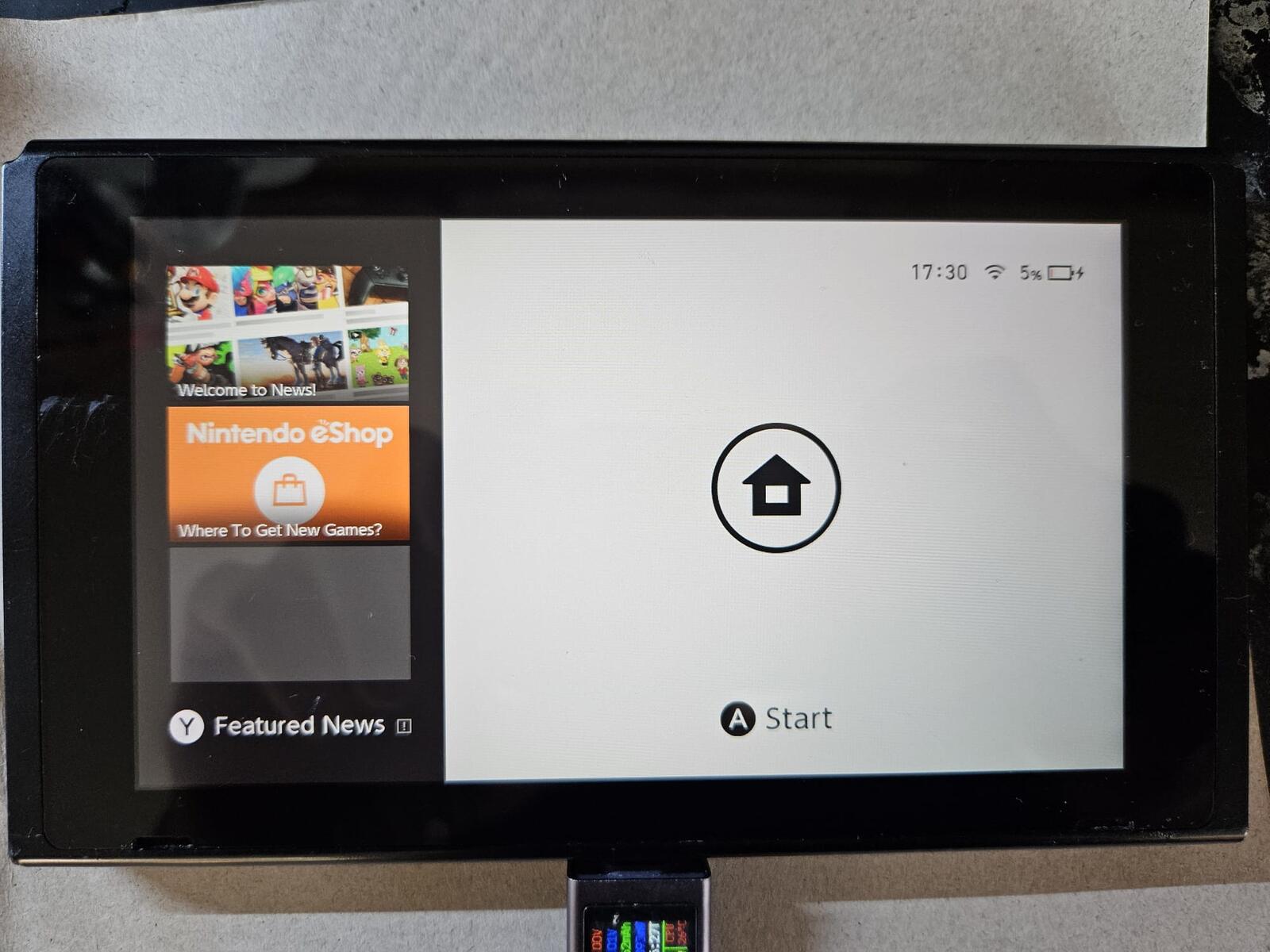 A Nintendo Switch on the bench showing the Home menu while charging after its USB-C port was replaced