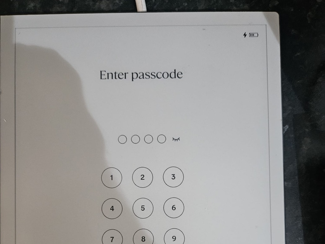 reMarkable 2 on the bench after the repair, on its passcode screen with the charging icon showing