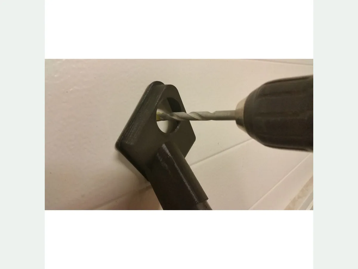 Black 35 millimetre vacuum dust collector held against a surface beside a drill