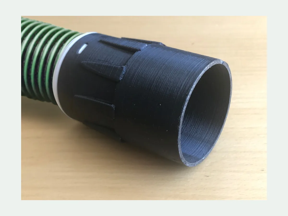 Black 3D printed straight vacuum adapter fitted to a green-striped hose
