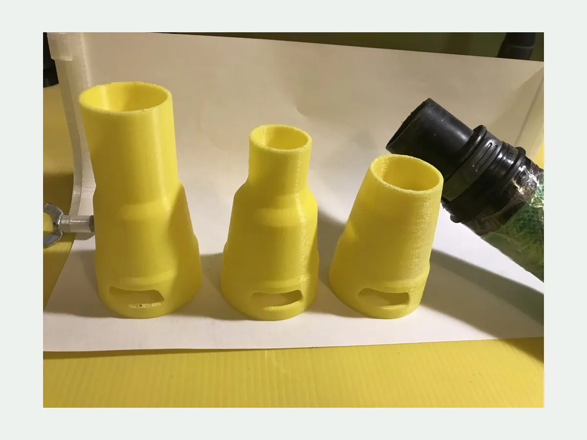 Yellow 3D printed adapters beside a black Karcher vacuum hose connector