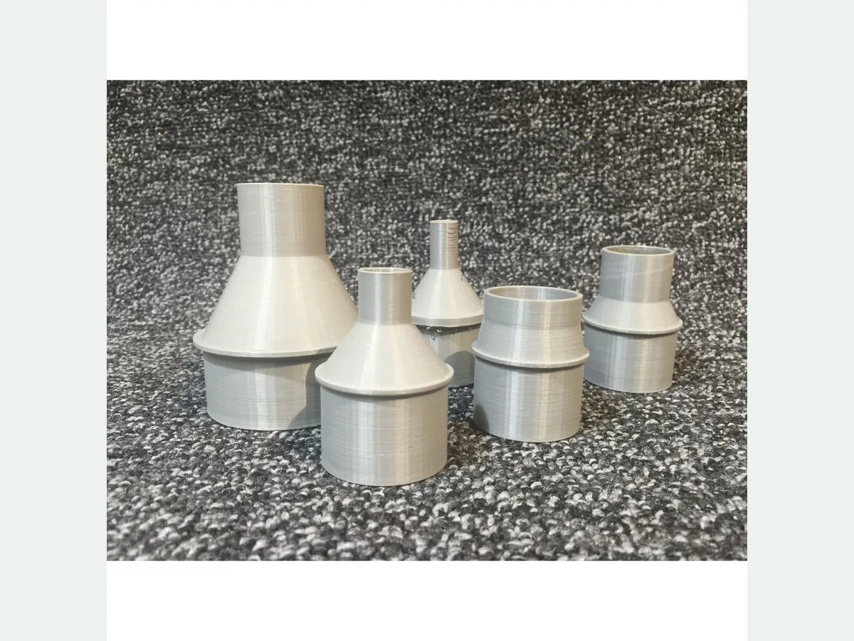 Several white 3D printed vacuum hose adapters in different measured diameters