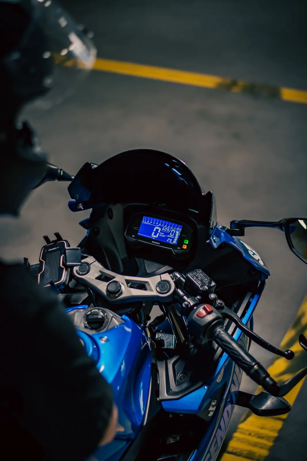 Motorcycle dashboard, handlebars and controls in a dimly lit garage