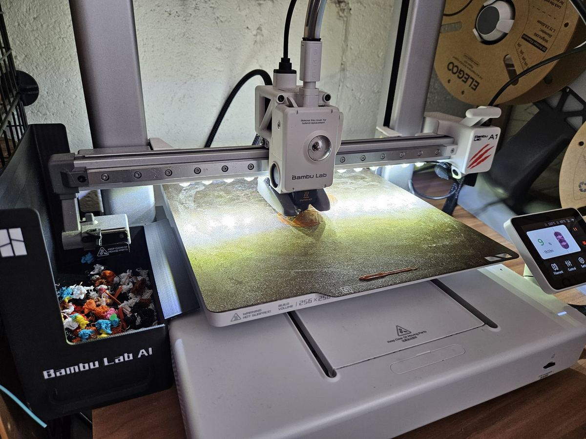 Bambu Lab A1 mid-print with the AMS and filament spools alongside