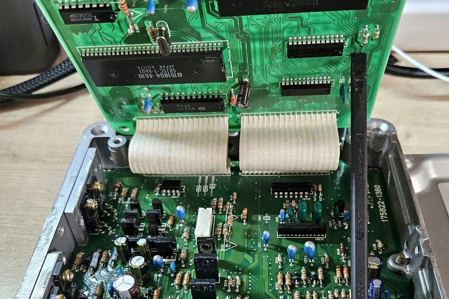 A Toyota Denso engine ECU opened on a workbench, its two circuit boards joined by ribbon cables