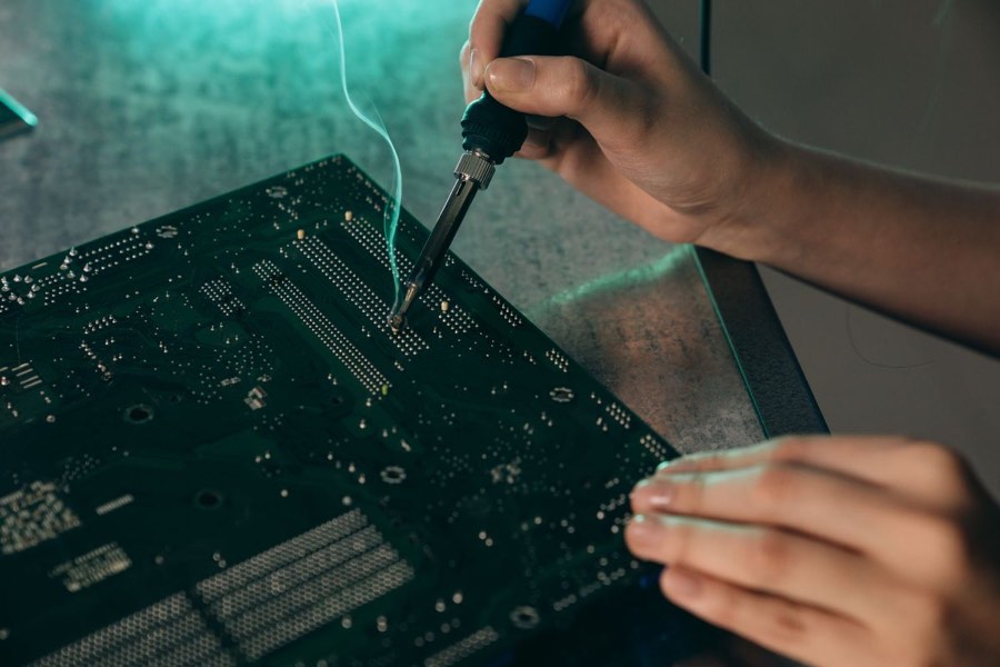 Soldering iron desoldering components on a dark circuit board
