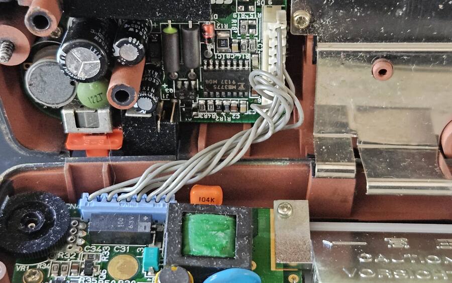 Inside a Sega Game Gear during a recap: power board capacitors and the ribbon to the main board