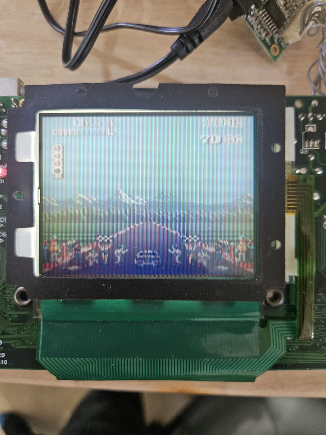 The Game Gear on the bench after the repair, running a racing game with a clean picture